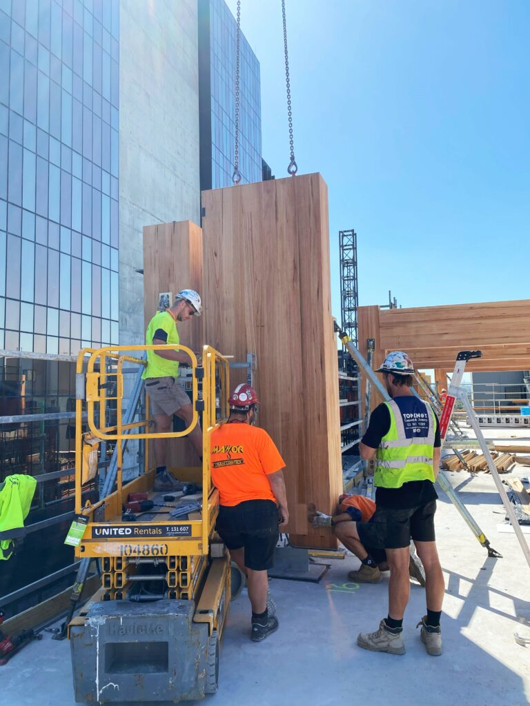 T3 Collingwood during construction showing MASSLAM columns being lifted into position. Image: ASH T3 Collingwood during construction lifting ASH's MASSLAM (mass timber) columns into place. Image credit: ASH